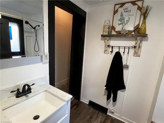 bathroom featuring wood-type flooring, vanity, ornamental molding, and walk in shower