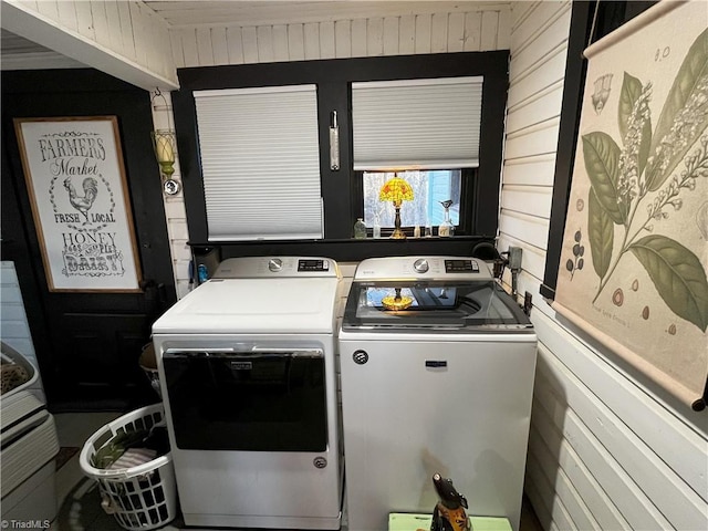 laundry room with wooden walls and washer and clothes dryer