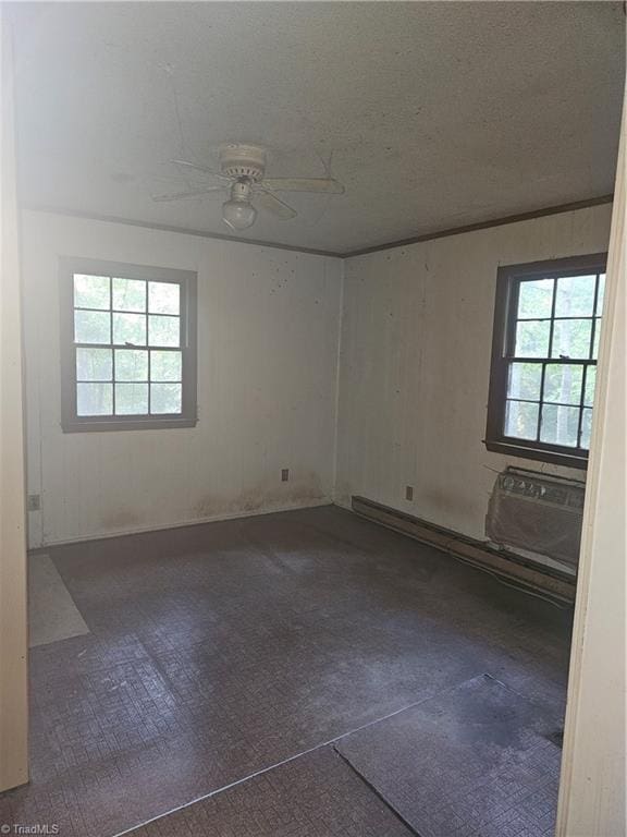 spare room with an AC wall unit, plenty of natural light, and ceiling fan