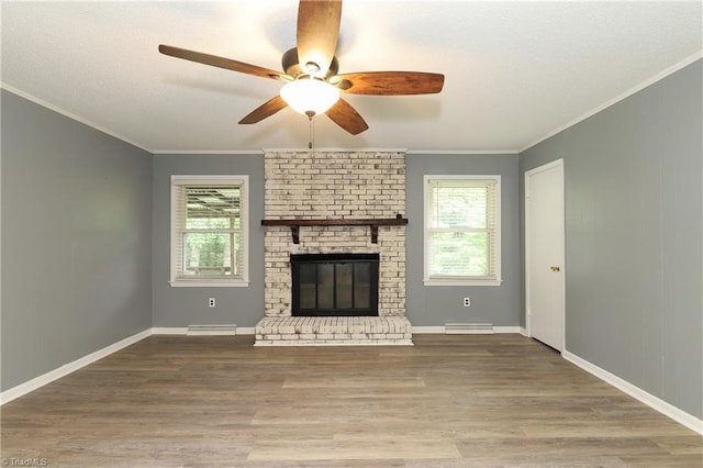 unfurnished living room featuring crown molding, a brick fireplace, a ceiling fan, and wood finished floors