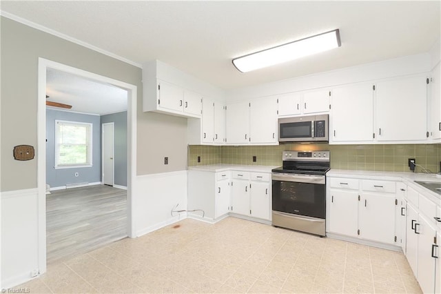 kitchen with crown molding, white cabinetry, stainless steel appliances, and backsplash