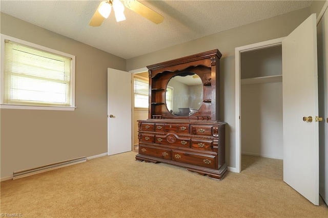 carpeted bedroom featuring a textured ceiling, a closet, a ceiling fan, and baseboard heating