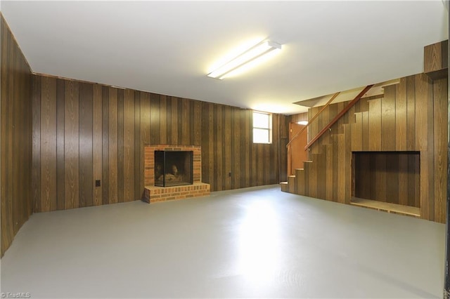 basement featuring wooden walls, a brick fireplace, and stairway