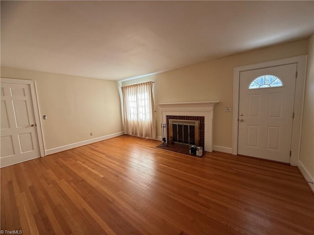 unfurnished living room featuring a brick fireplace and hardwood / wood-style flooring