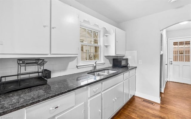 kitchen with backsplash, wood-type flooring, sink, and white cabinets