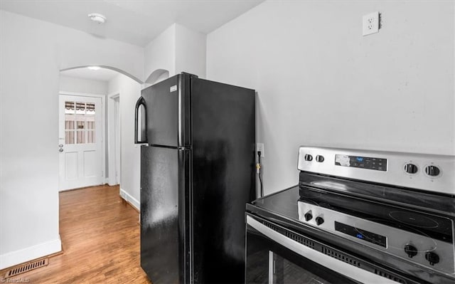 kitchen featuring electric stove, black refrigerator, and light hardwood / wood-style floors