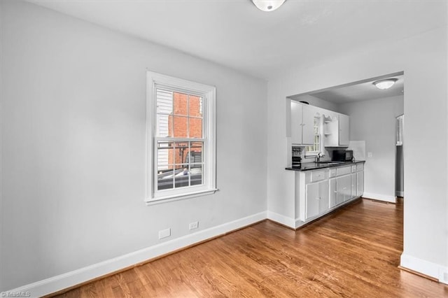 kitchen featuring hardwood / wood-style flooring, sink, and white cabinets