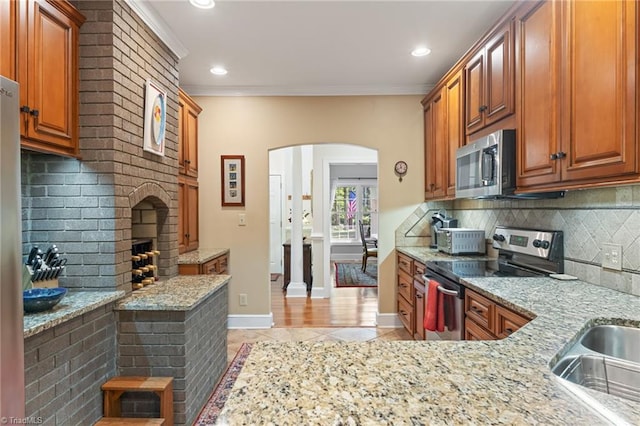 3805 Tangle Oak Dr, Clemmons, NC 27012 - kitchen with stainless steel appliances, arched walkways, light stone counters, crown molding, and backsplash