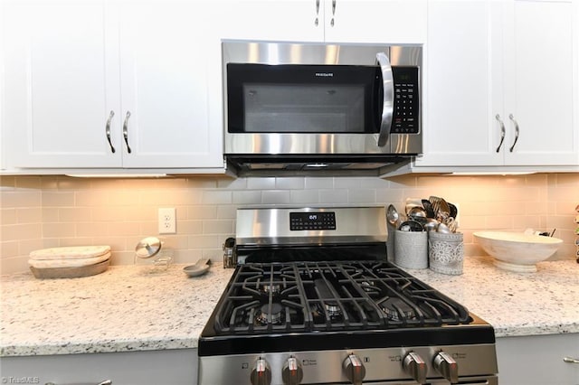 kitchen featuring backsplash, white cabinets, light stone countertops, and stainless steel appliances