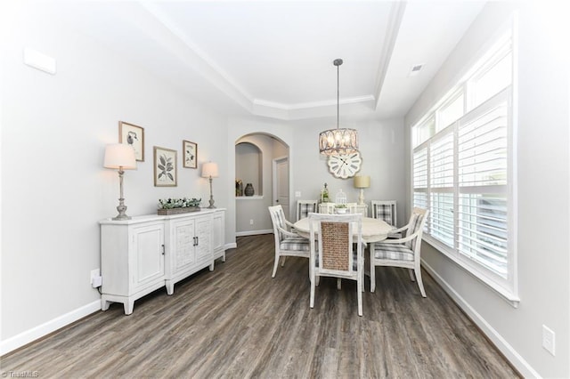 dining area with arched walkways, a chandelier, baseboards, wood finished floors, and a tray ceiling