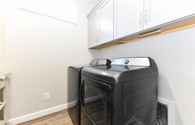 clothes washing area featuring light wood-style floors, baseboards, cabinet space, and washing machine and clothes dryer