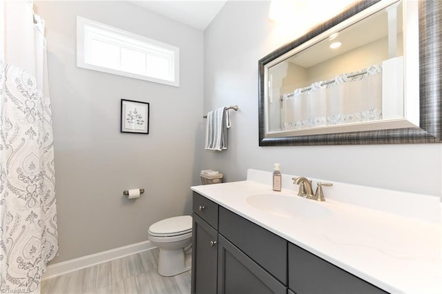 bathroom with baseboards, toilet, and vanity
