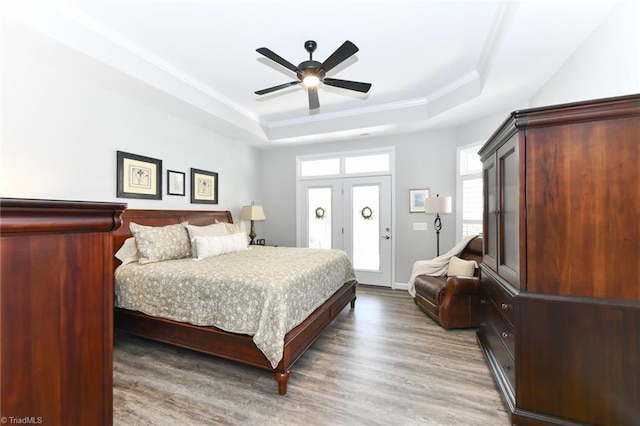 bedroom with a raised ceiling, ornamental molding, a ceiling fan, and wood finished floors