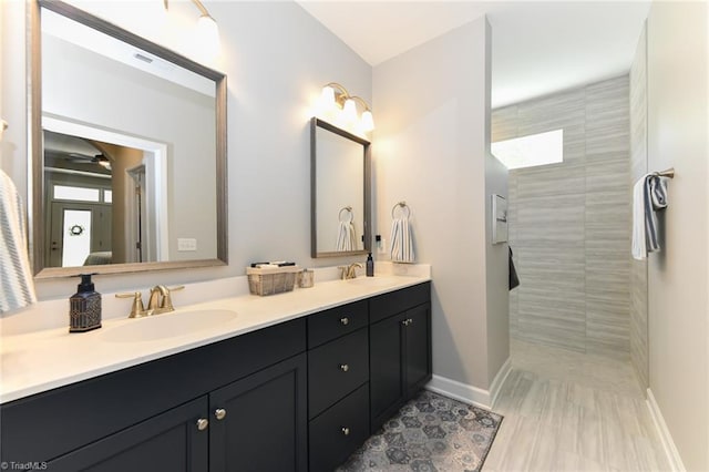 full bath featuring a walk in shower, double vanity, baseboards, and a sink