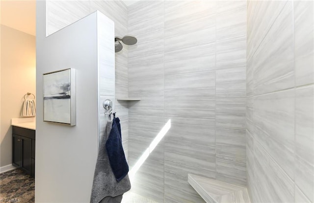 full bathroom with a tile shower and vanity