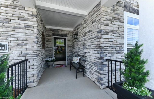 entrance to property with a porch and stone siding