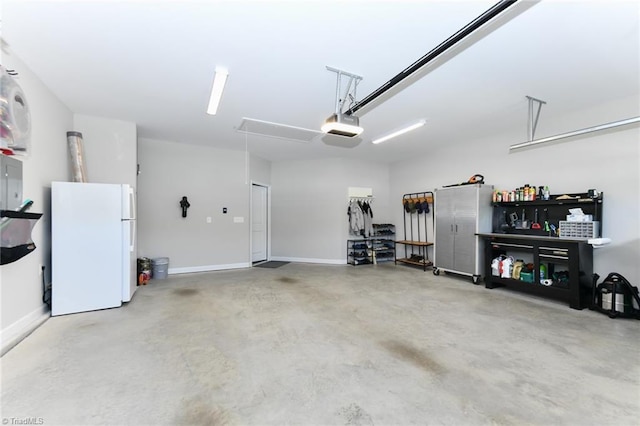 garage featuring freestanding refrigerator, baseboards, and a garage door opener