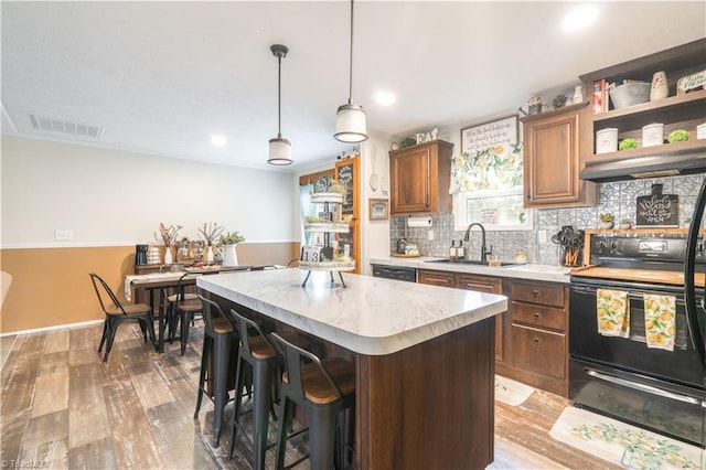 kitchen with pendant lighting, sink, range hood, a center island, and range with electric cooktop