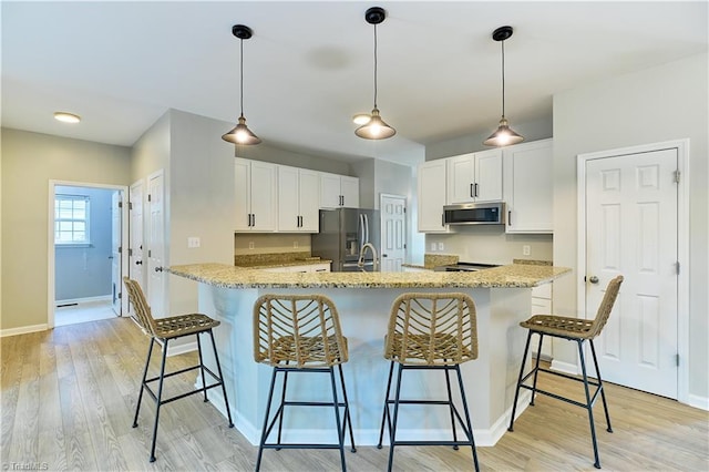 kitchen with baseboards, white cabinets, a breakfast bar, and stainless steel appliances
