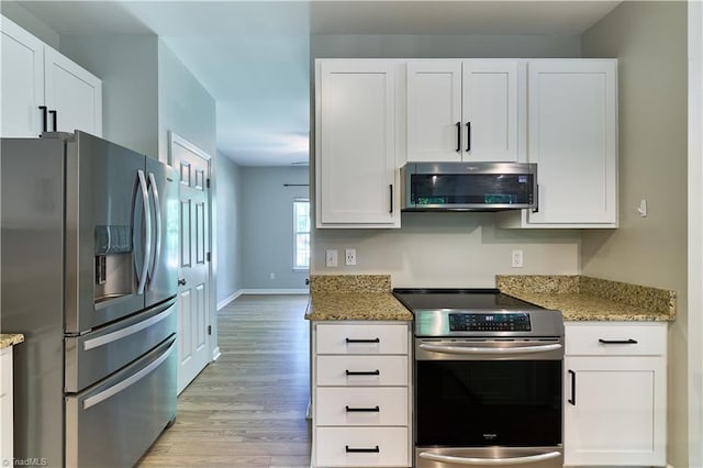 kitchen featuring light stone counters, white cabinets, stainless steel appliances, and light wood-type flooring