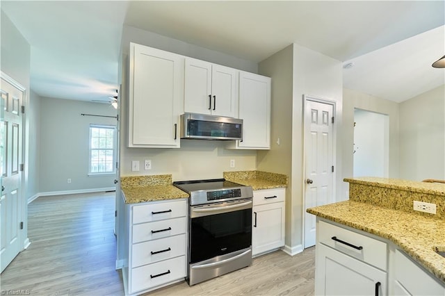 kitchen featuring light stone counters, light wood finished floors, appliances with stainless steel finishes, and white cabinetry