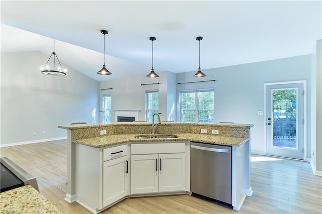 kitchen featuring a sink, a fireplace, light wood-style floors, dishwasher, and open floor plan