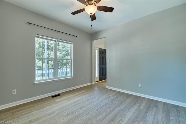 unfurnished room with a ceiling fan, baseboards, visible vents, and wood finished floors