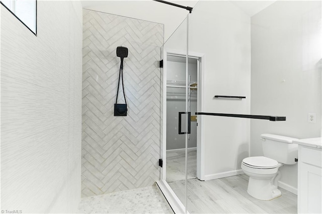 bathroom featuring toilet, baseboards, a shower stall, and vanity