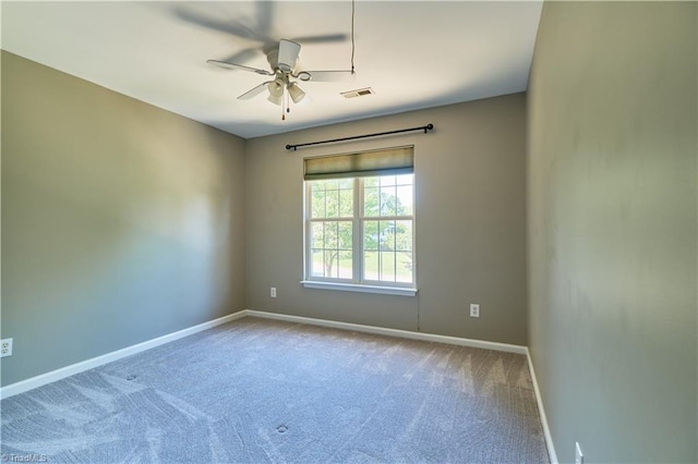 carpeted spare room featuring baseboards, ceiling fan, and visible vents