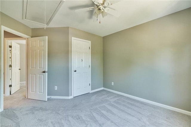unfurnished bedroom featuring baseboards, light carpet, ceiling fan, and attic access