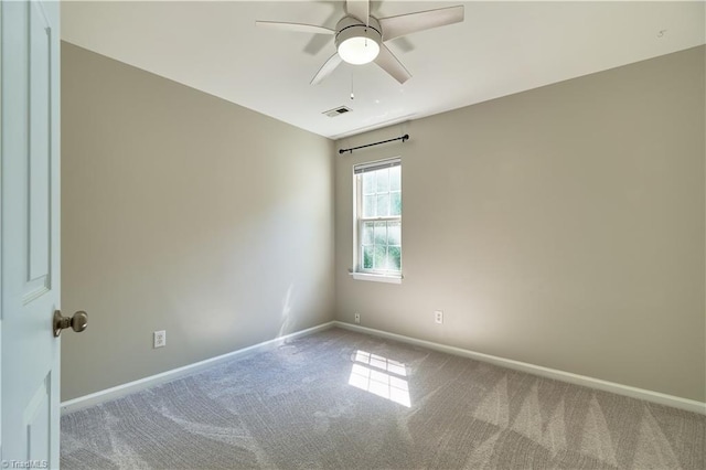 carpeted empty room with baseboards, a ceiling fan, and visible vents