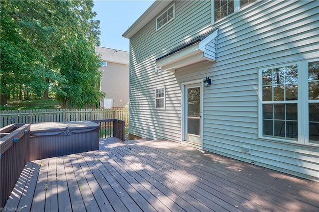 wooden terrace featuring a covered hot tub and fence