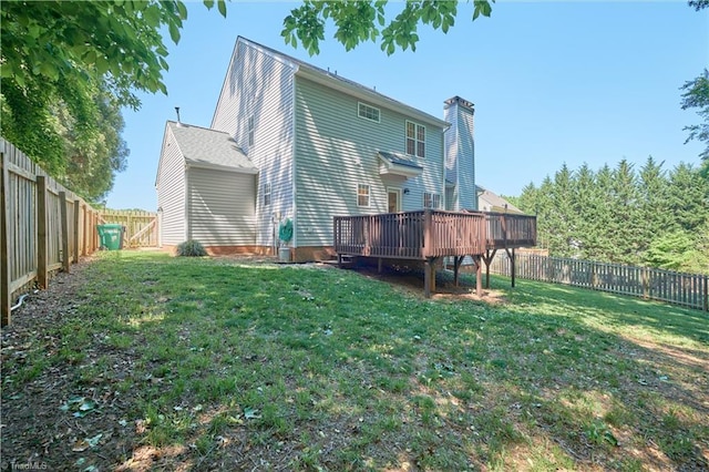 rear view of house with a fenced backyard, a chimney, a lawn, and a deck