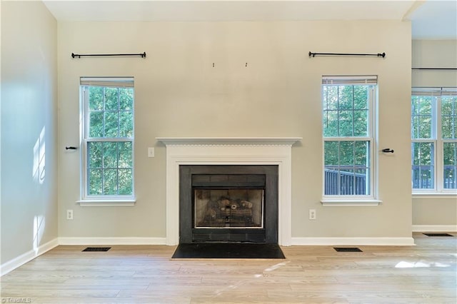 interior space with baseboards, wood finished floors, visible vents, and a healthy amount of sunlight