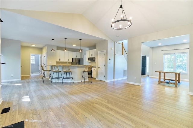 living room with visible vents, plenty of natural light, a chandelier, and light wood-type flooring