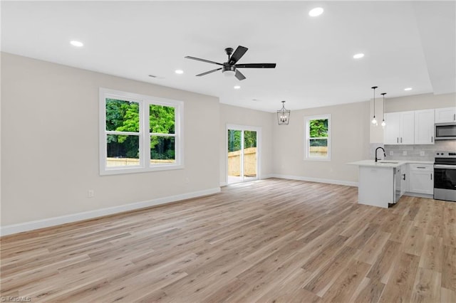 3630 Old Vineyard Rd, Winston-Salem, NC 27104 - unfurnished living room featuring a ceiling fan, baseboards, light wood-type flooring, a sink, and a chandelier