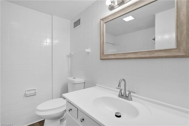 1101 N Elm St Unit 904, Greensboro, NC 27401 - bathroom with tile walls, vanity, toilet, and decorative backsplash