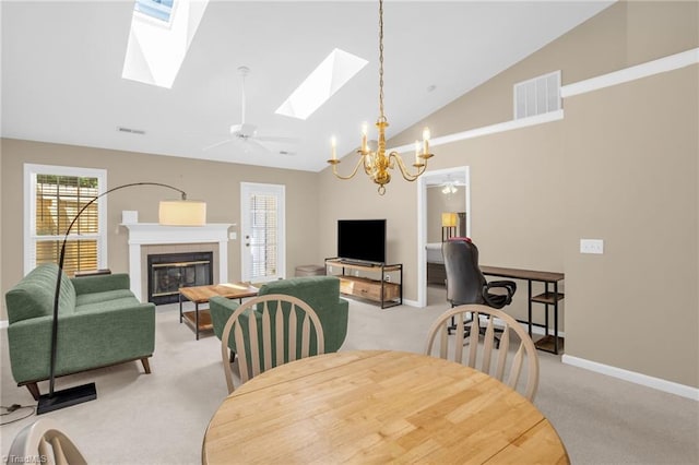 dining area featuring light carpet, a tile fireplace, a skylight, baseboards, and a chandelier