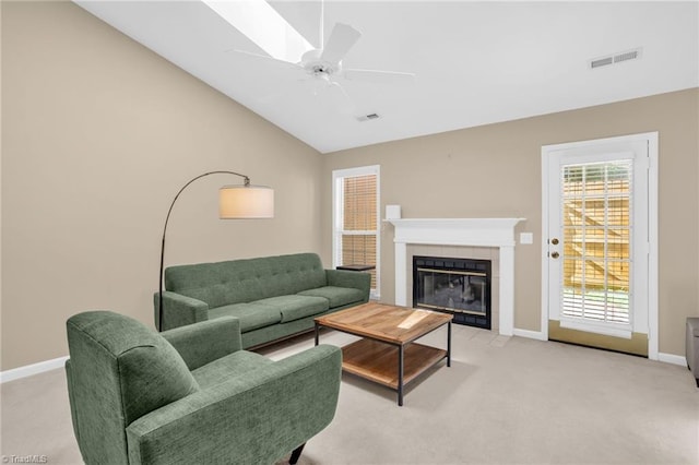 living area with light colored carpet, baseboards, lofted ceiling, a tiled fireplace, and ceiling fan