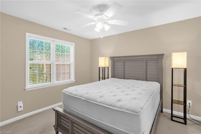 bedroom featuring light colored carpet, baseboards, and a ceiling fan