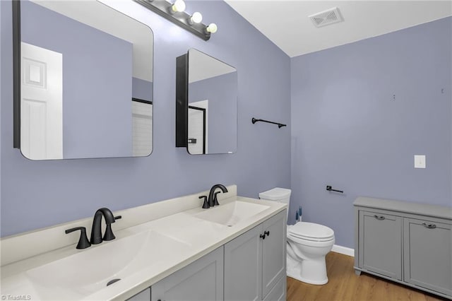 bathroom featuring toilet, wood finished floors, and double vanity