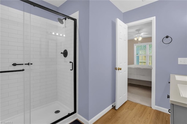 bathroom with connected bathroom, wood finished floors, a shower stall, and baseboards