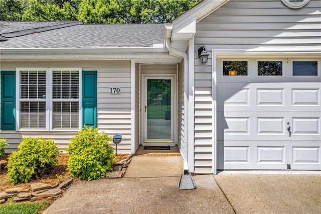 doorway to property with a shingled roof and an attached garage