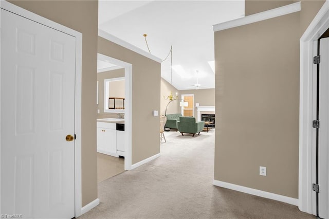 hall featuring light colored carpet and baseboards