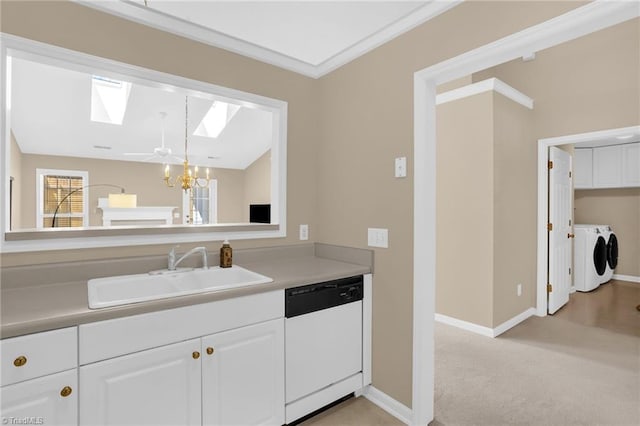 kitchen featuring white dishwasher, a sink, independent washer and dryer, a skylight, and a chandelier
