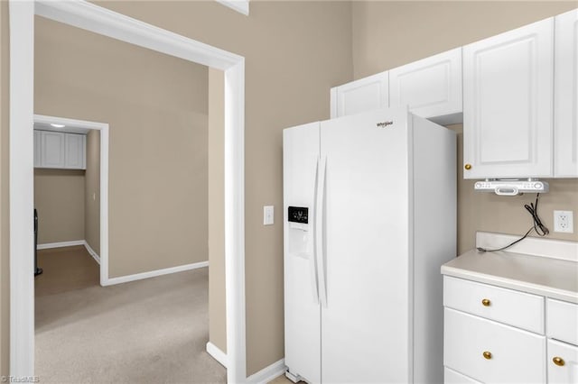 kitchen with white fridge with ice dispenser, light colored carpet, white cabinetry, and light countertops