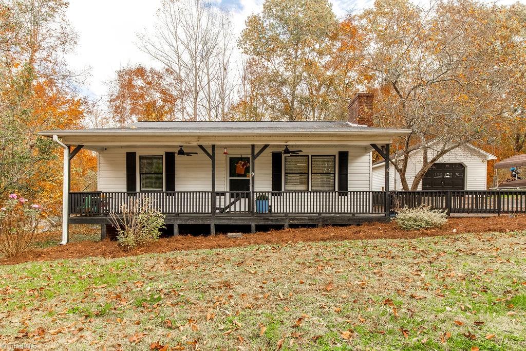 view of front of home with a garage, a front yard, covered porch, and an outbuilding