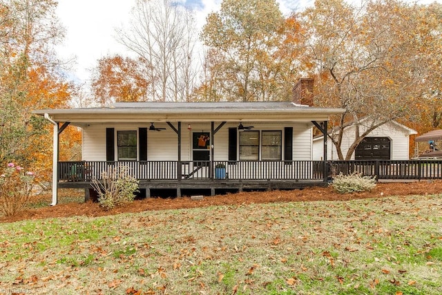 view of front of home with a garage, a front yard, covered porch, and an outbuilding