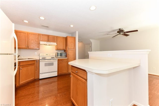 kitchen featuring recessed lighting, under cabinet range hood, white appliances, wood finished floors, and light countertops