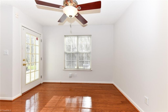 empty room with a healthy amount of sunlight, baseboards, and wood finished floors